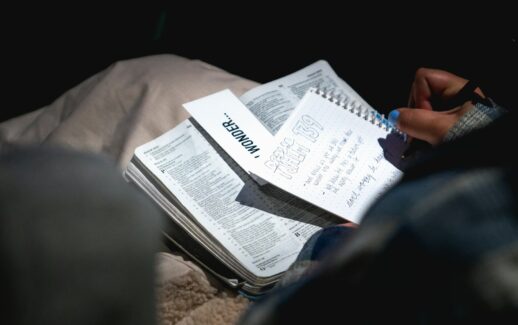 person holding black pen and writing on white notebook