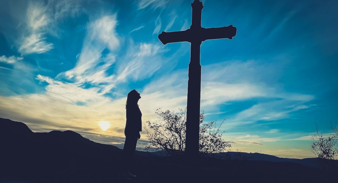 a person standing in front of a cross
