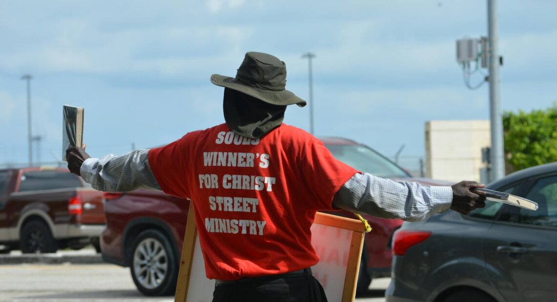 A street preacher spreading religious messages in a Florida parking lot.