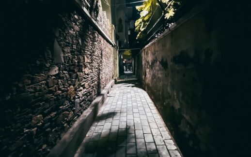 a dark alley with a brick walkway leading to a building