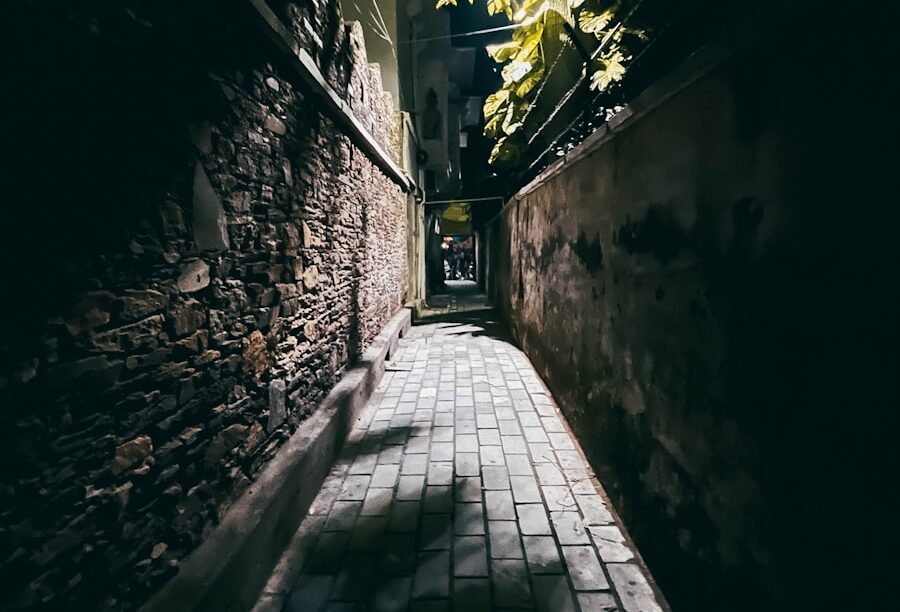 a dark alley with a brick walkway leading to a building